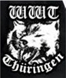 Schriftzug „WWT“ in altdeutscher weißer Schrift auf schwarzem Grund. Darunter ein Wolfskopf mit geöffnetem Maul. Darunter die Sektionsbezeichnung „Thüringen“ in altdeutscher weißer Schrift.